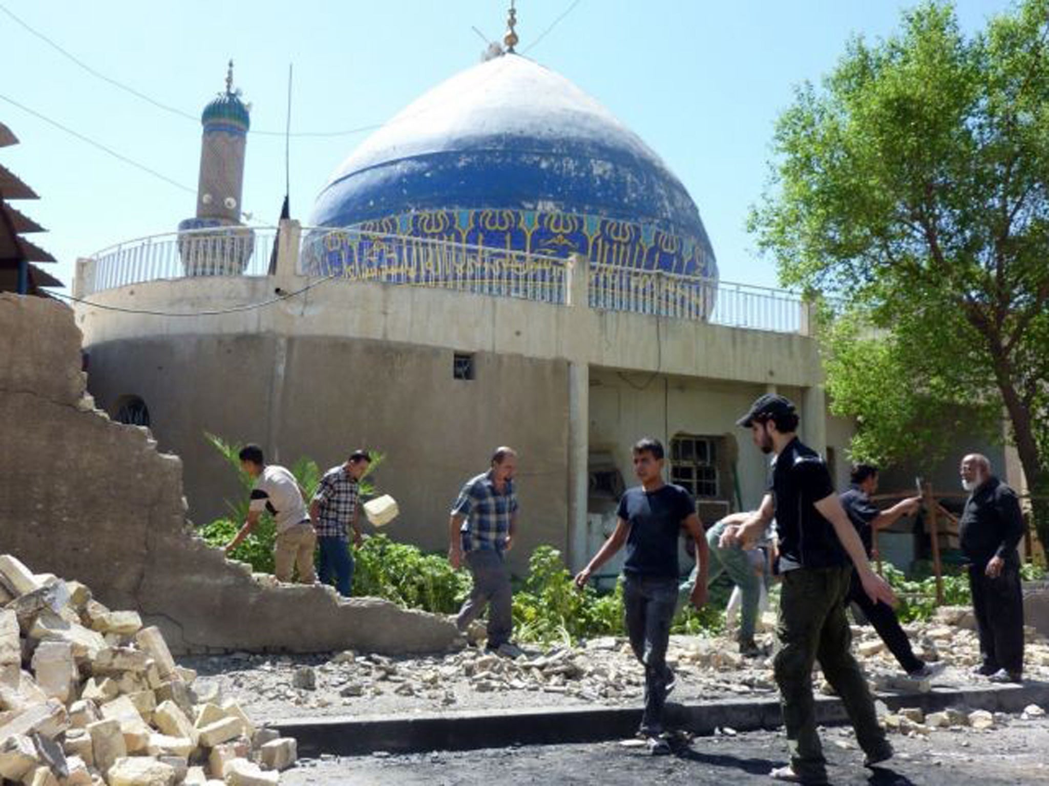 Iraqis remove the stones of a wall destroyed in a car bombing outside Ahl al-Bayya' mosque on 29 July 2013 in south-eastern Baghdad