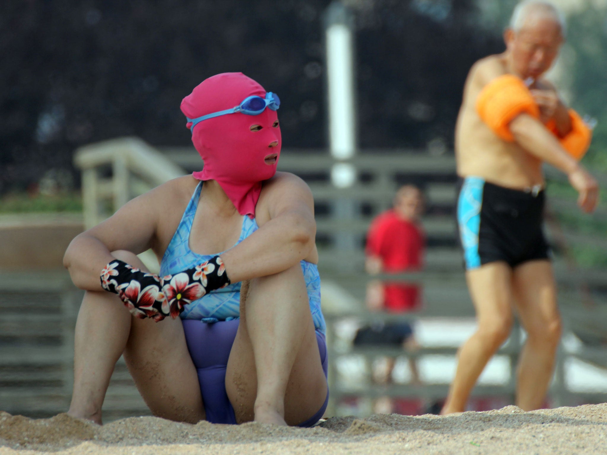 This picture taken on July 3, 2013 shows a Chinese beachgoer wearing a body suit and protective head mask, dubbed 'face-kinis' by Chinese netizens, on a public beach in Qingdao, northeast China's Shandong province. The face masks were initially designed to protect from sunburn but it turns out they are also quite handy at repelling insects and jellyfish, as many people in China dislike getting a tan, especially on the face.