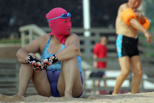 This picture taken on July 3, 2013 shows a Chinese beachgoer wearing a body suit and protective head mask, dubbed 'face-kinis' by Chinese netizens, on a public beach in Qingdao, northeast China's Shandong province. The face masks were initially designed to protect from sunburn but it turns out they are also quite handy at repelling insects and jellyfish, as many people in China dislike getting a tan, especially on the face.
