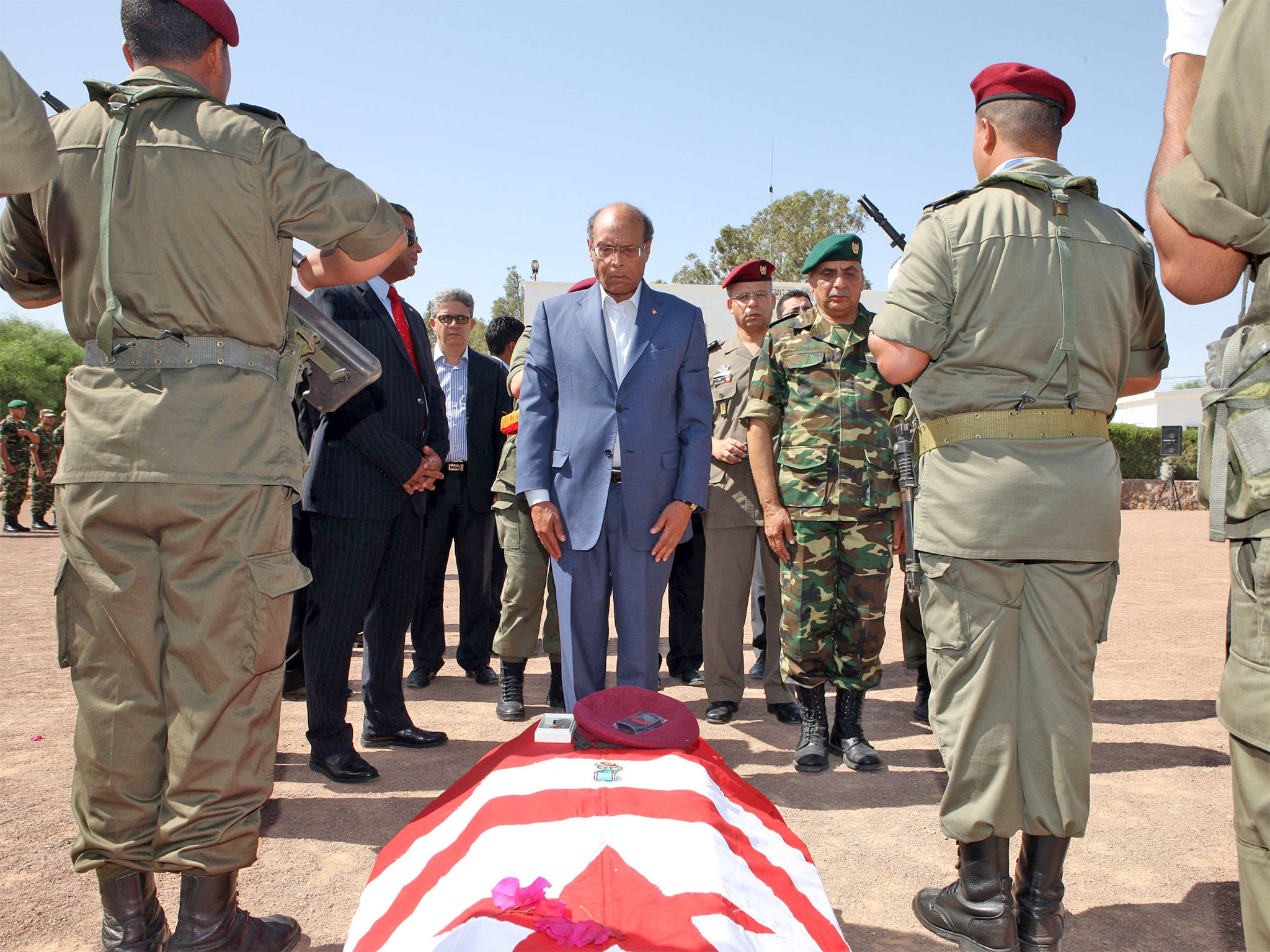 President Moncef Marzouki stands in front of coffin, draped in the Tunisian flag, of the one of the eight soldiers who died in an ambush by an armed group in Mount Chaambi
