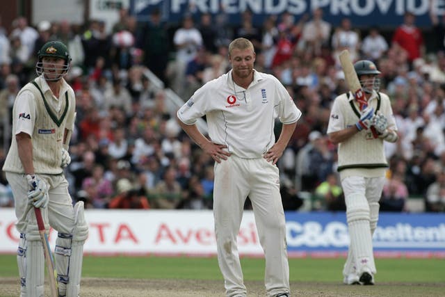 Andrew Flintoff of England looks dejected as Brett Lee (L) and Glenn McGrath hold on in 2005