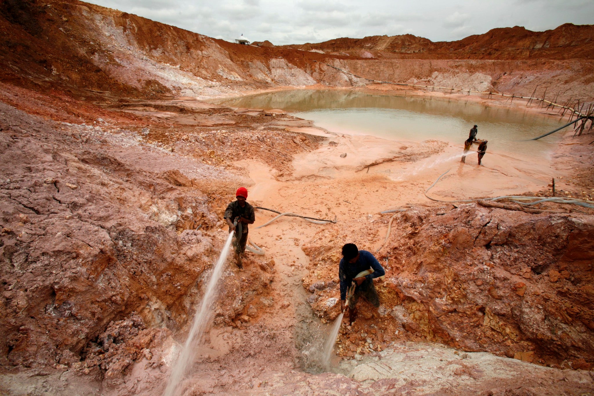 Indonesian miners hose down a mining site as they sort out tin ore from sand on Bangka island February 21, 2007. REUTERS/Beawiharta