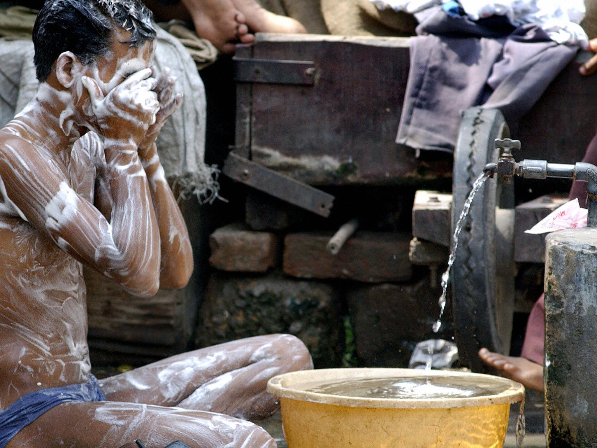 A boy has a wash with clean water and soap in India