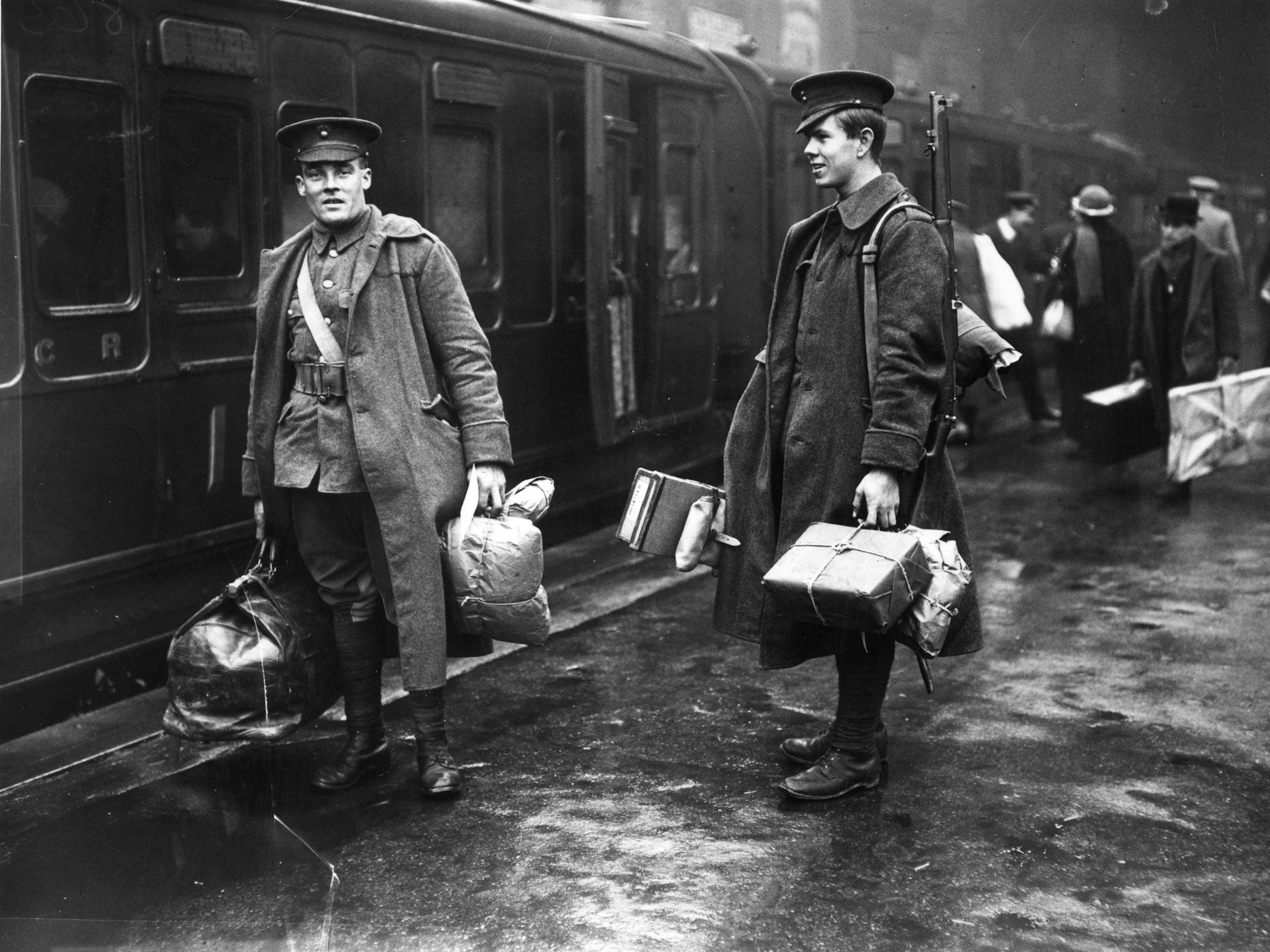 Two soldiers on the concourse at Victoria station, London, about to leave for the front line. They are carrying parcels full of food and other provisions.