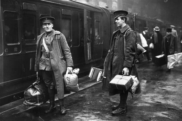 Two soldiers on the concourse at Victoria station, London, about to leave for the front line. They are carrying parcels full of food and other provisions. 