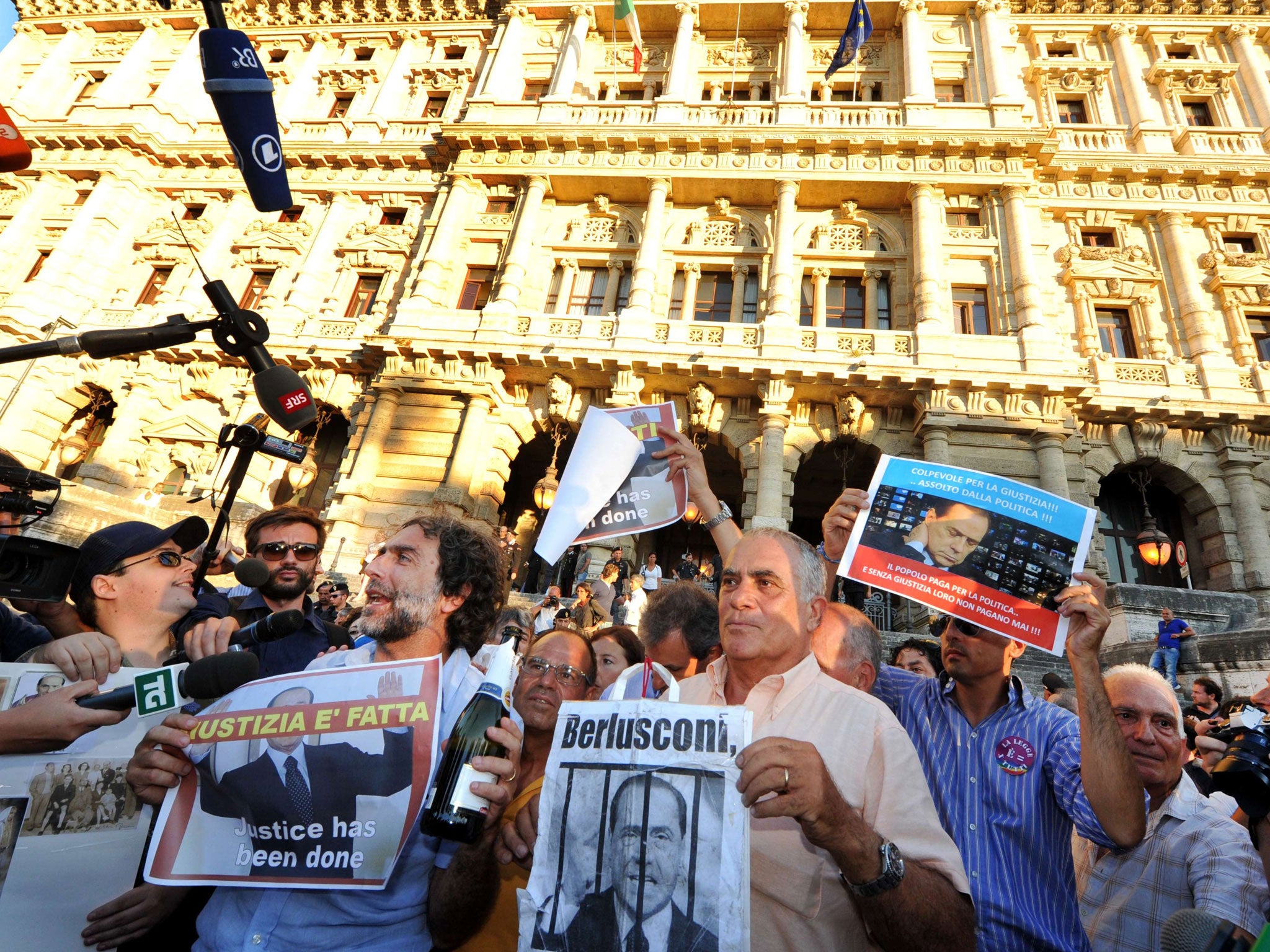 People hold signs as they celebrate the Italian Supreme Court's sentencing of Italian politician Silvio Berlusconi, in front of the Cassation building in Rome