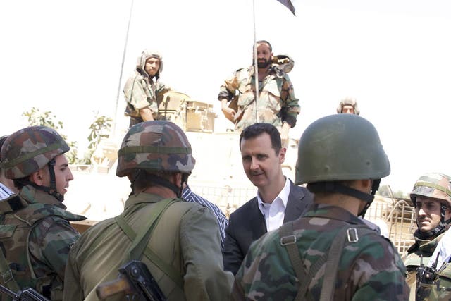 Syria's President Bashar al-Assad chats with military personnel during his visit to a military site in the town of Daraya, southwest of Damascus