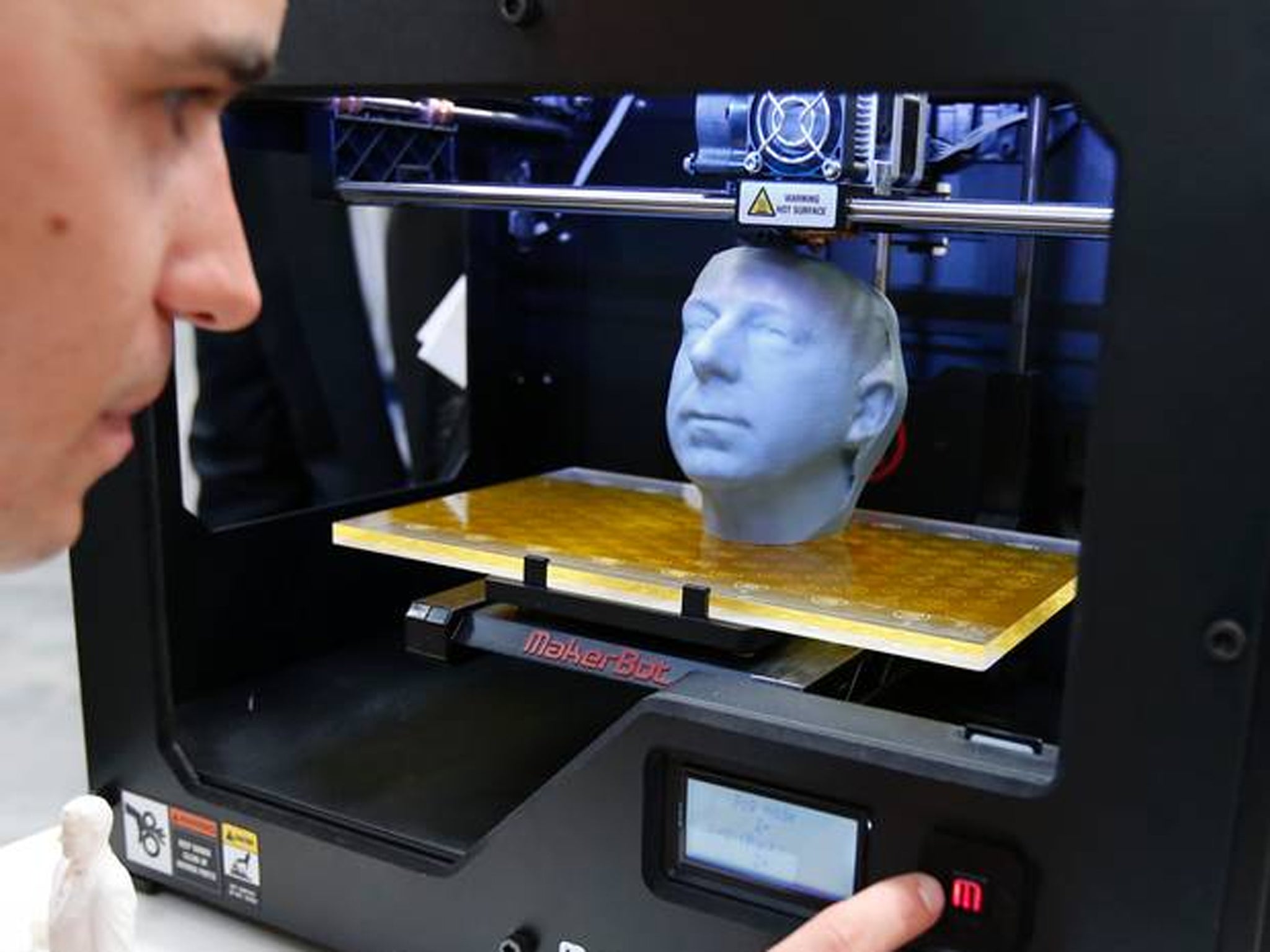 Manuel Leute poses for the media as he uses the 3D printer MakerBot Replicator