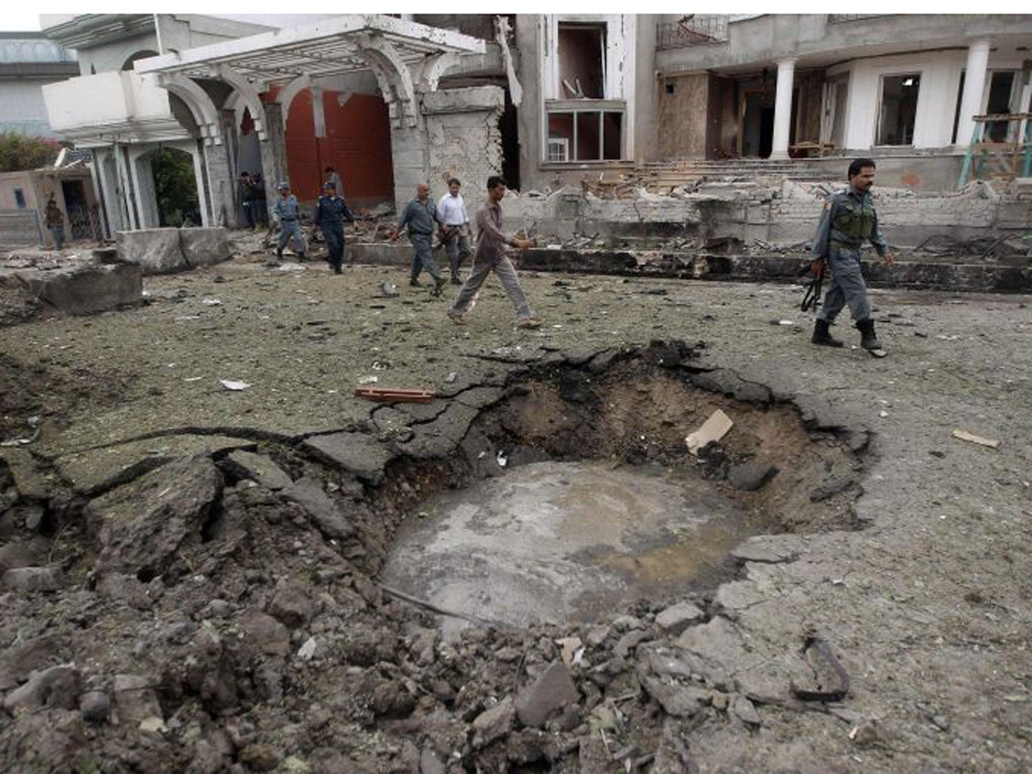 Afghan policemen walk near a crater at the site of a suicide attack at the Indian consulate in the Jalalabad province