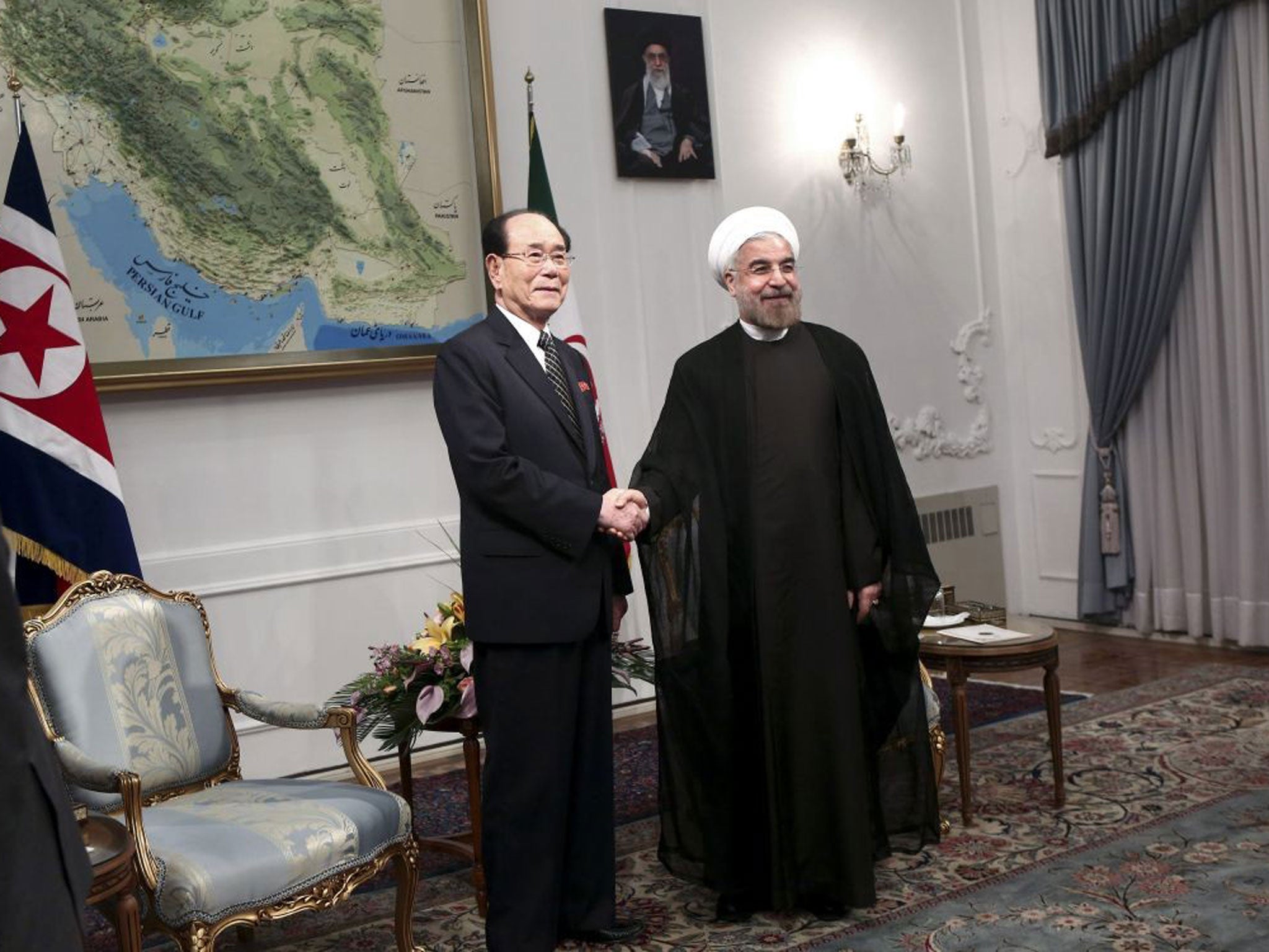Iranian President Hasan Rouhani, right, shakes hands with a top North Korean leader, Kim Yong Nam, at the start of a meeting in Tehran