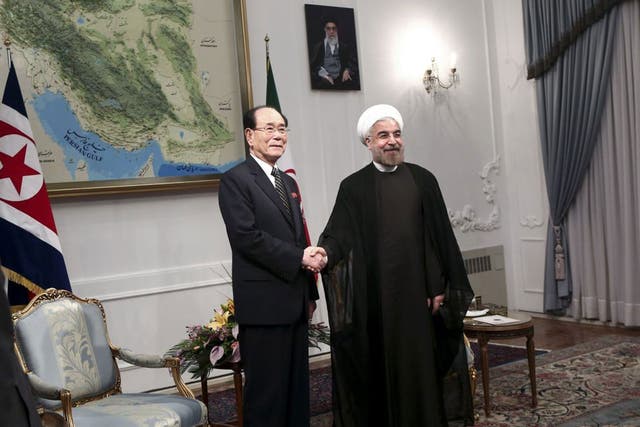 Iranian President Hasan Rouhani, right, shakes hands with a top North Korean leader, Kim Yong Nam, at the start of a meeting in Tehran