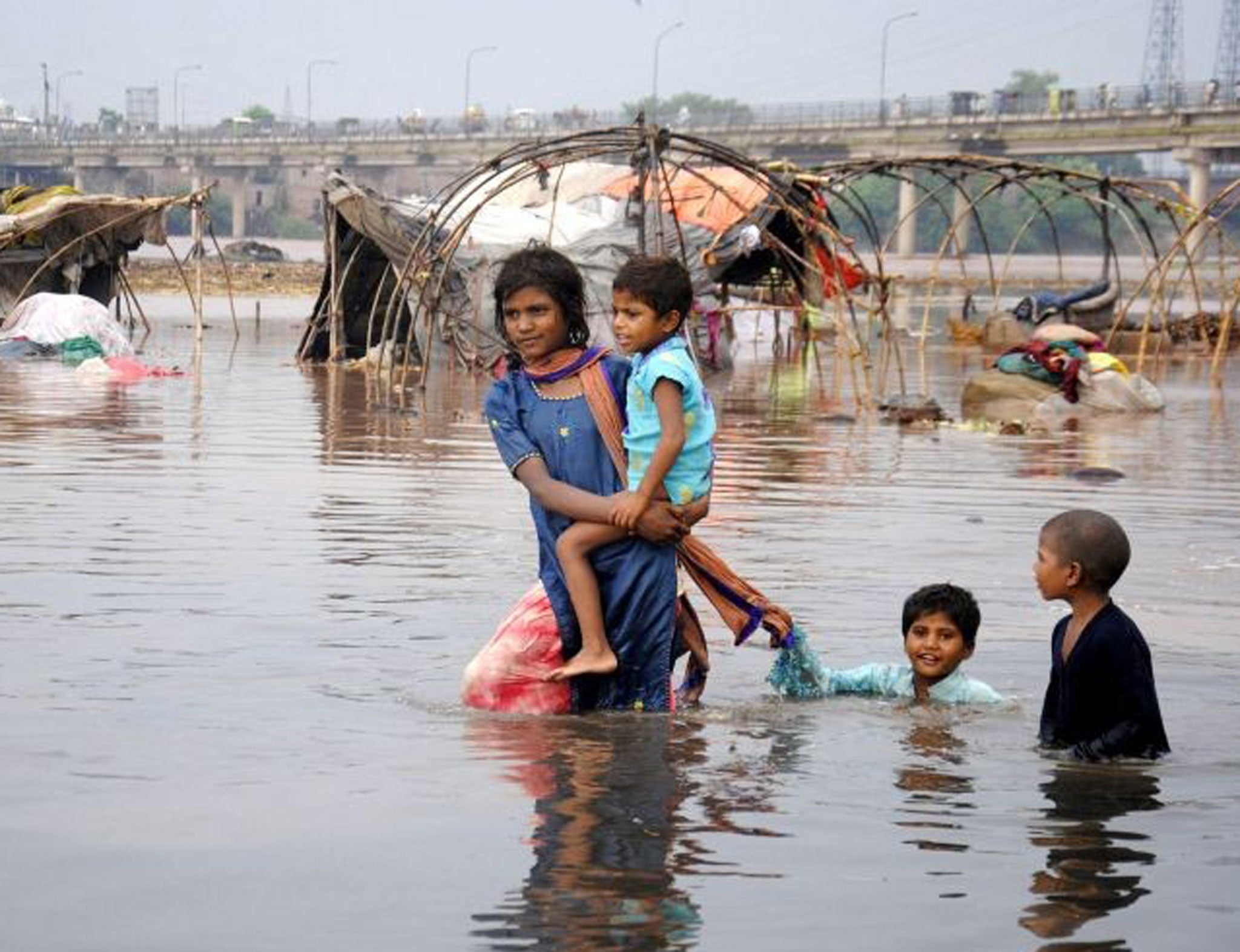 Pakistani children walk in the flooded Ravi river in eastern Pakistan's Lahore