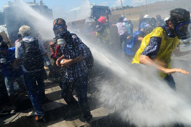 Demonstrators are hit by water cannon during clashes against Turkish police forces 