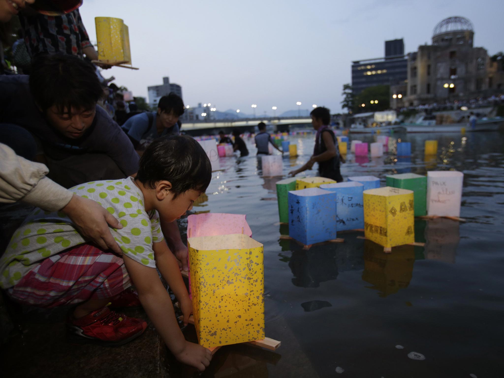 A boy releases a paper lantern on to the Motoyasu River