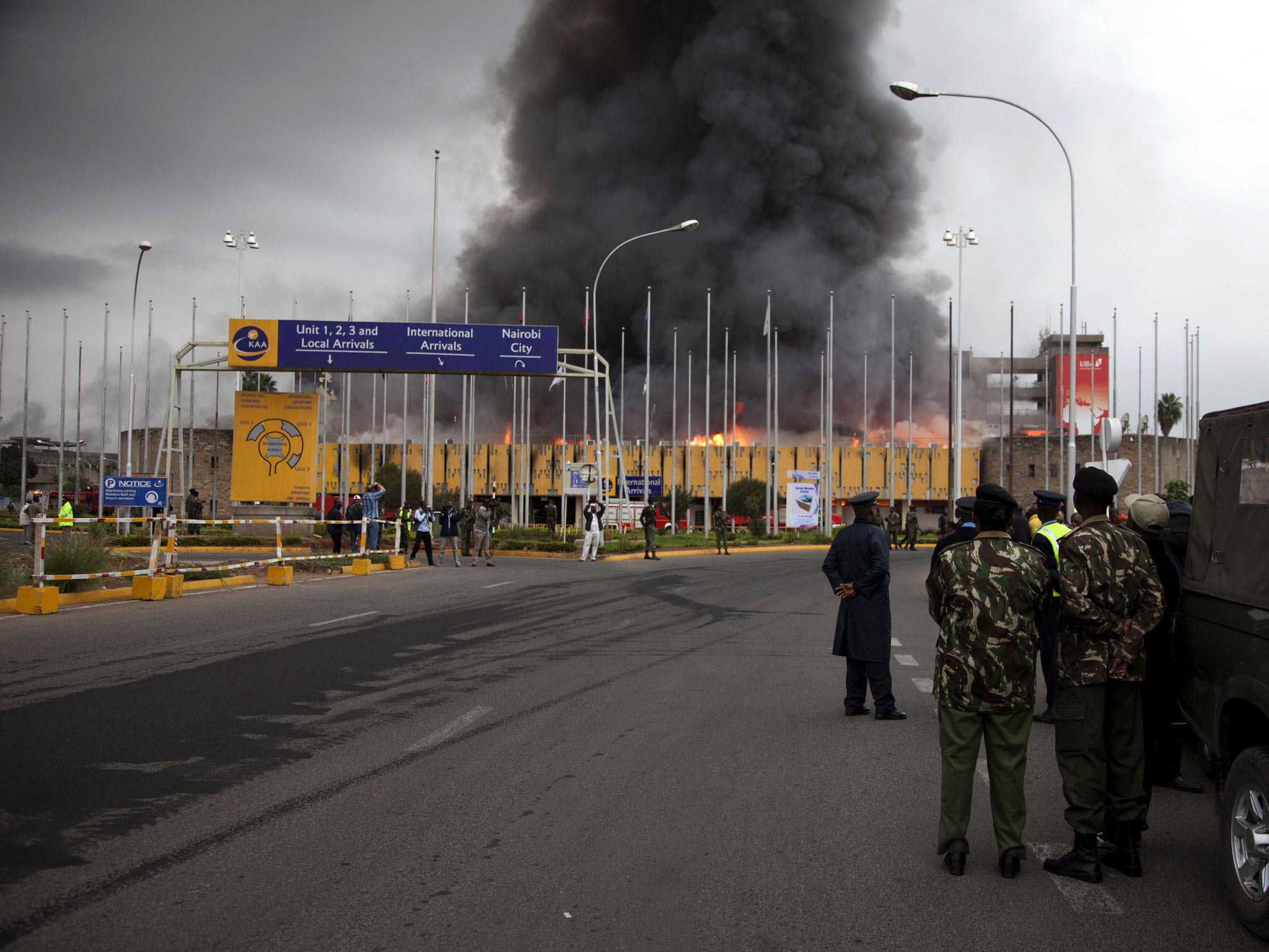 Policemen stand guard as fire rages at the International arrivals unit of Jomo Kenyatta International Airport, Nairobi, Kenya