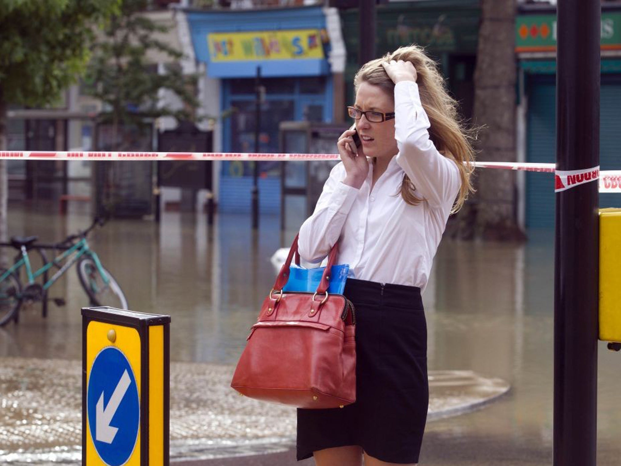 A woman on her phone at Half Moon Lane in Herne Hill, London as a burst water main has resulted in severe flooding