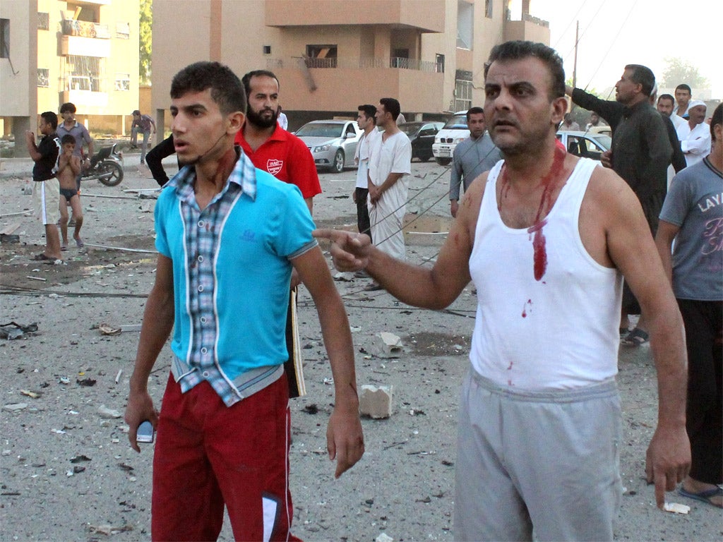 Injured men walk away from the scene of an explosion in the northern Syrian city of Raqqa