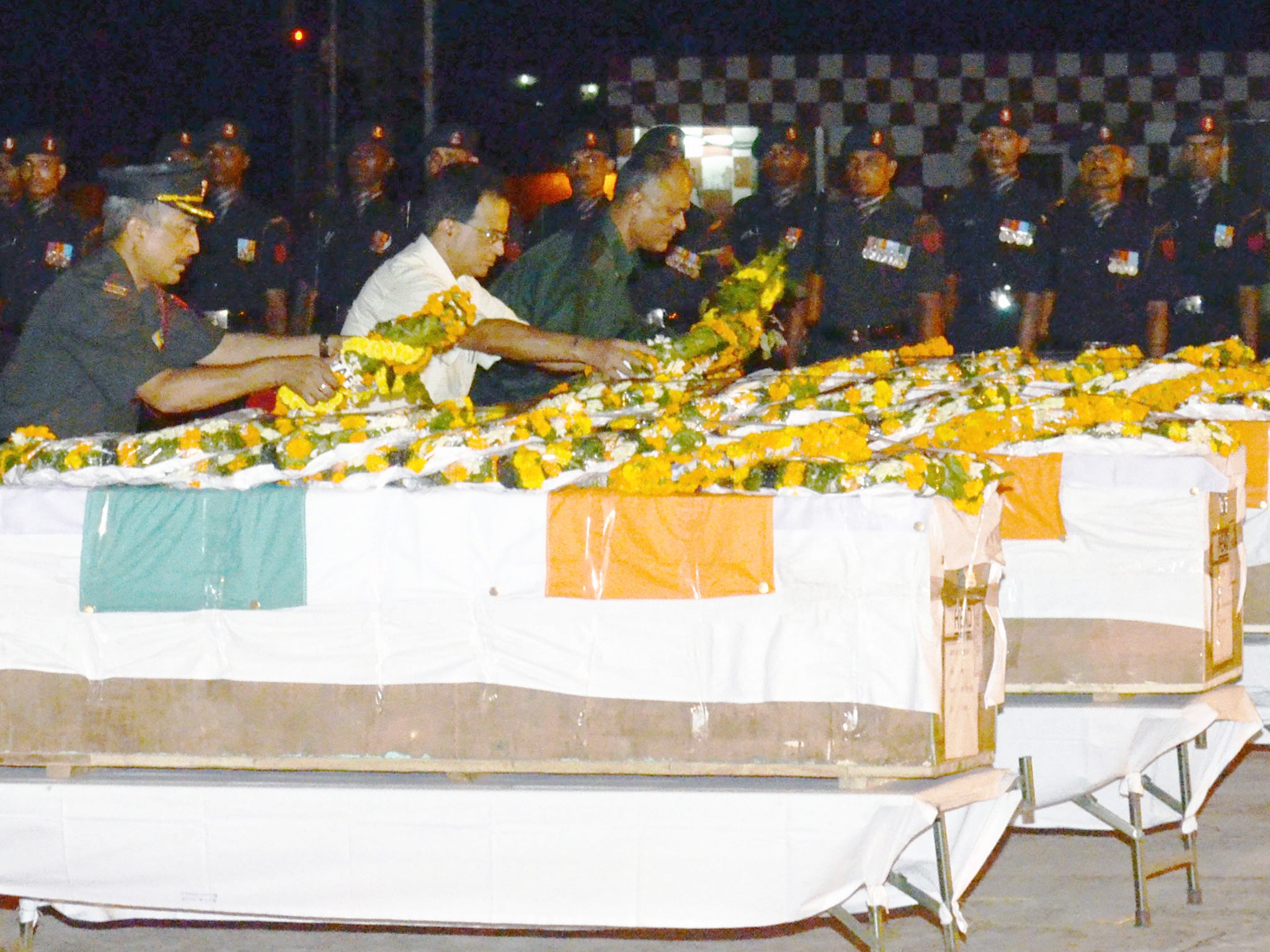 Indian Army officers lay wreaths and pay their respects over the caskets of five soldiers killed in during a cross-border attack in Kashmir, following the arrival of their remains at the Patna Airport