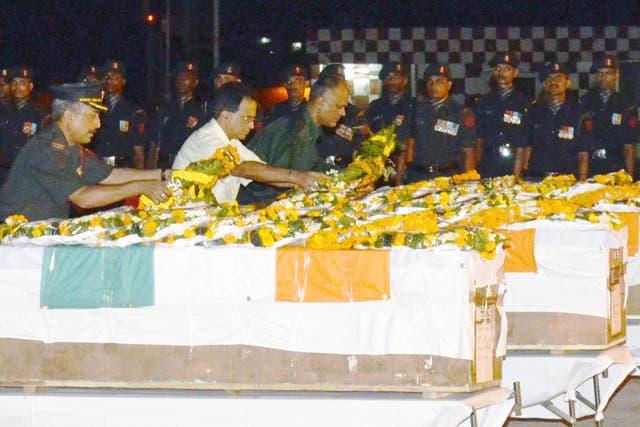 Indian Army officers lay wreaths and pay their respects over the caskets of five soldiers killed in during a cross-border attack in Kashmir, following the arrival of their remains at the Patna Airport