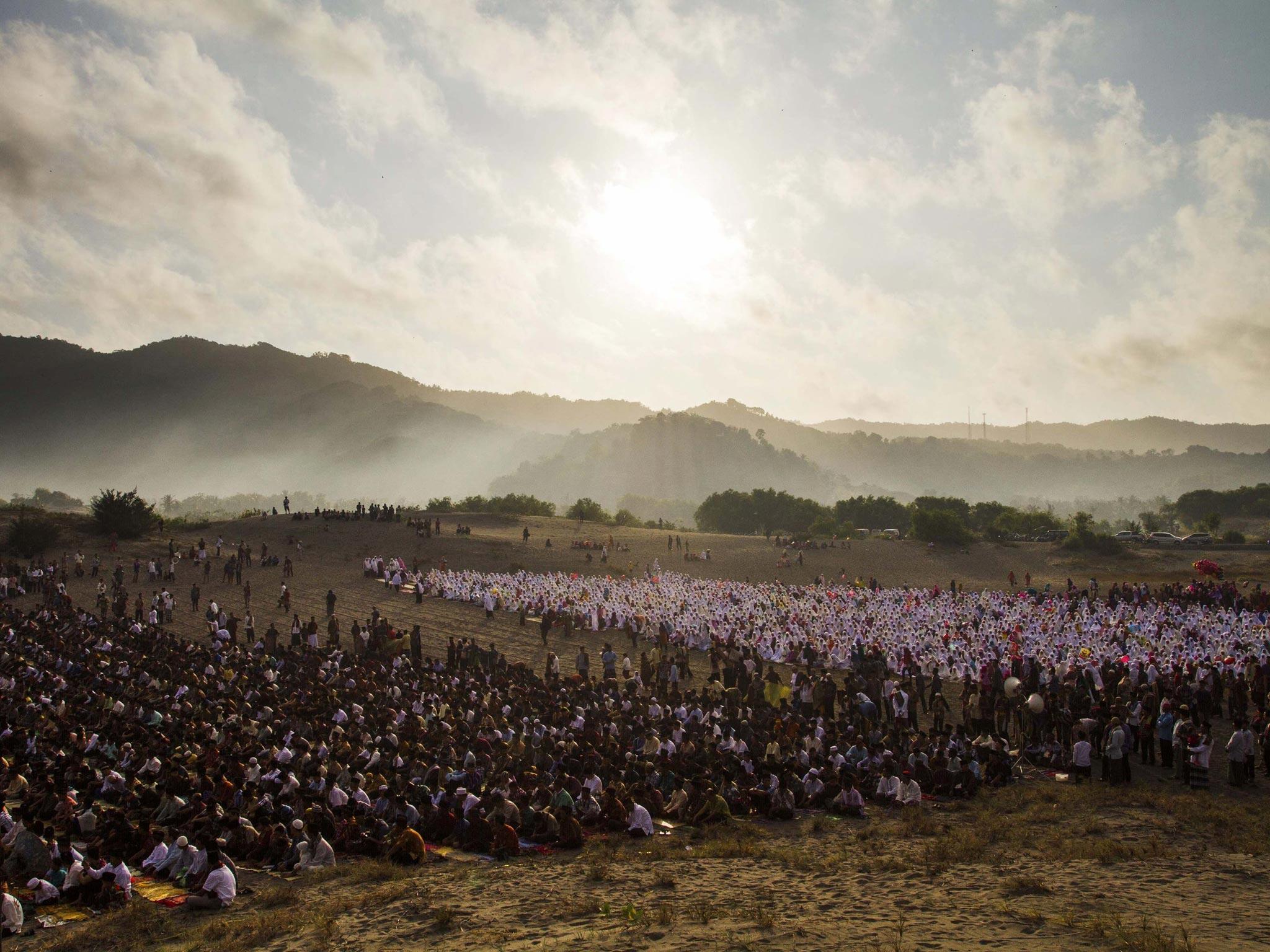People walk through sand to attend Eid al-Fitr prayers in Indonesia