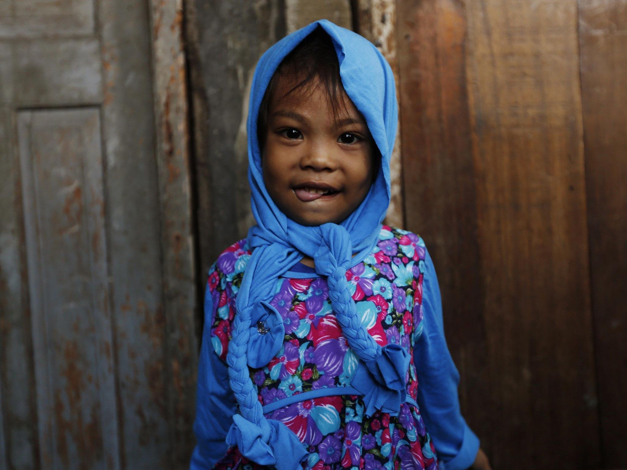A child poses in front of her house after attending Eid al-Fitr prayers near Sunda Kelapa port in Jakarta
