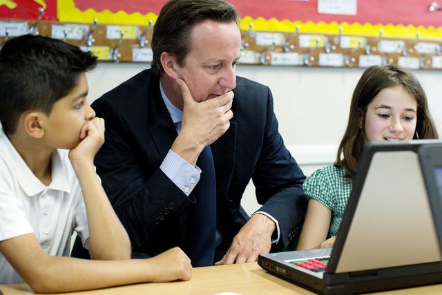 Britain's Prime Minister David Cameron sits with pupils Abdullah Rashid (9) and Anna Seitoar (9) in a computer class during his visit to St Mary's and St John's CE School in north London on July 8, 2013.