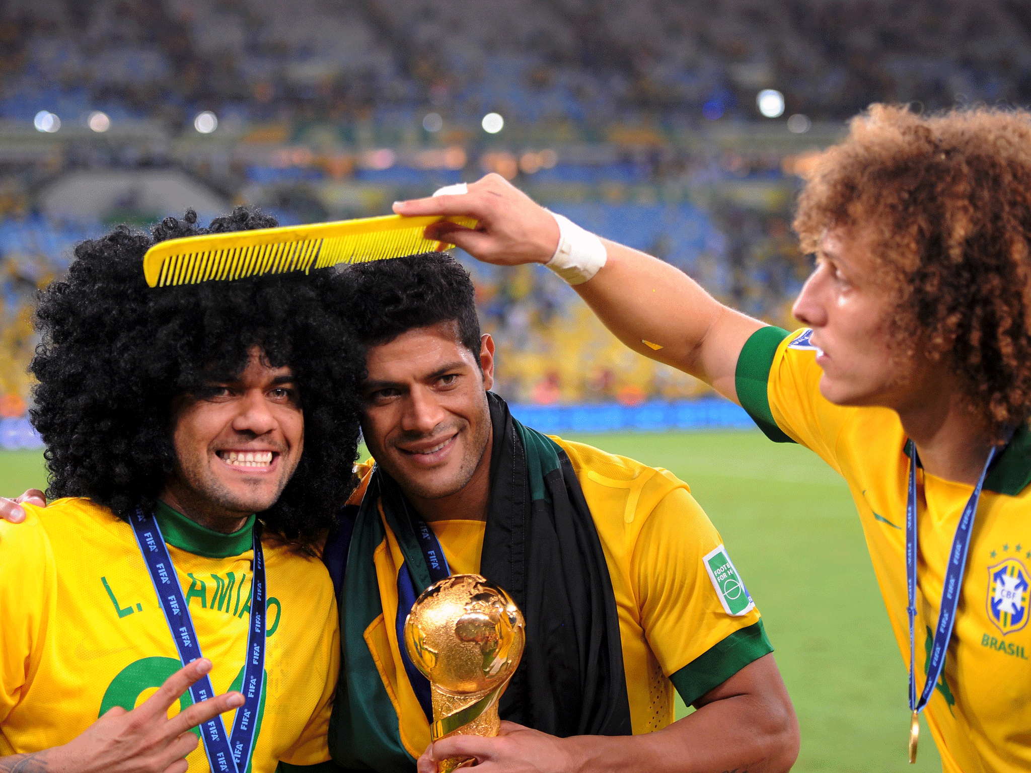 David Luiz (right) uses an extra large comb on the wig of team-mate Dani Alves (left), who is posing next Hulk (centre) after Brazil's Confederations Cup victory GETTY