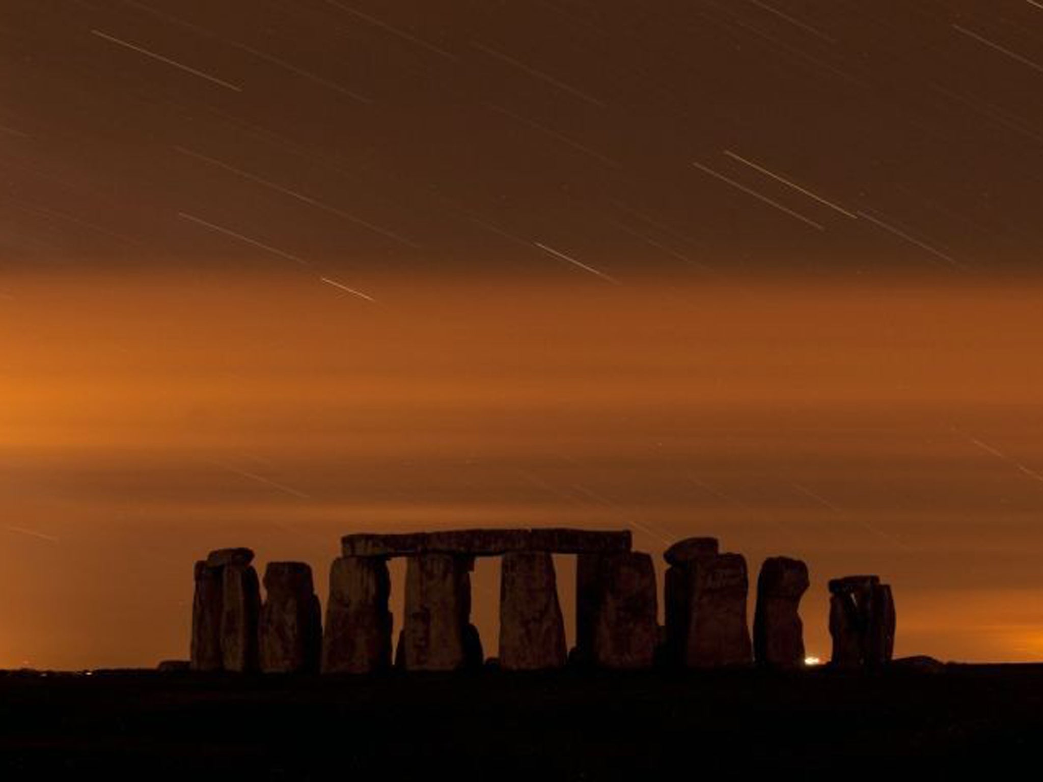 The Perseid meteor shower in the night sky above Stone Henge in Salisbury Plain