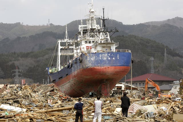 Survivors among the rubble look at the destroyed trawler after the tsunami devastated Kesennuma