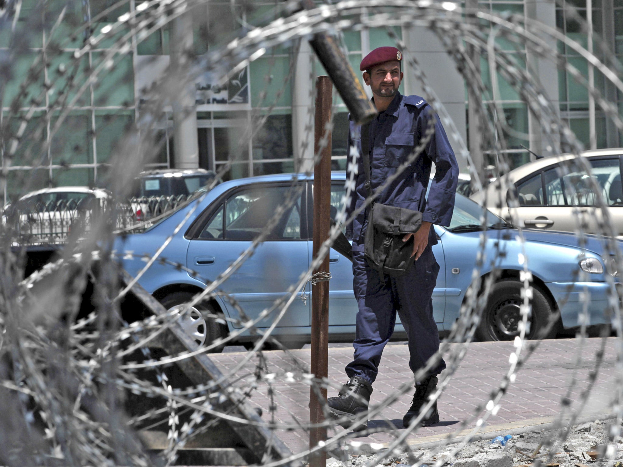 A policeman stands behind razor wire as security is stepped up in Manama