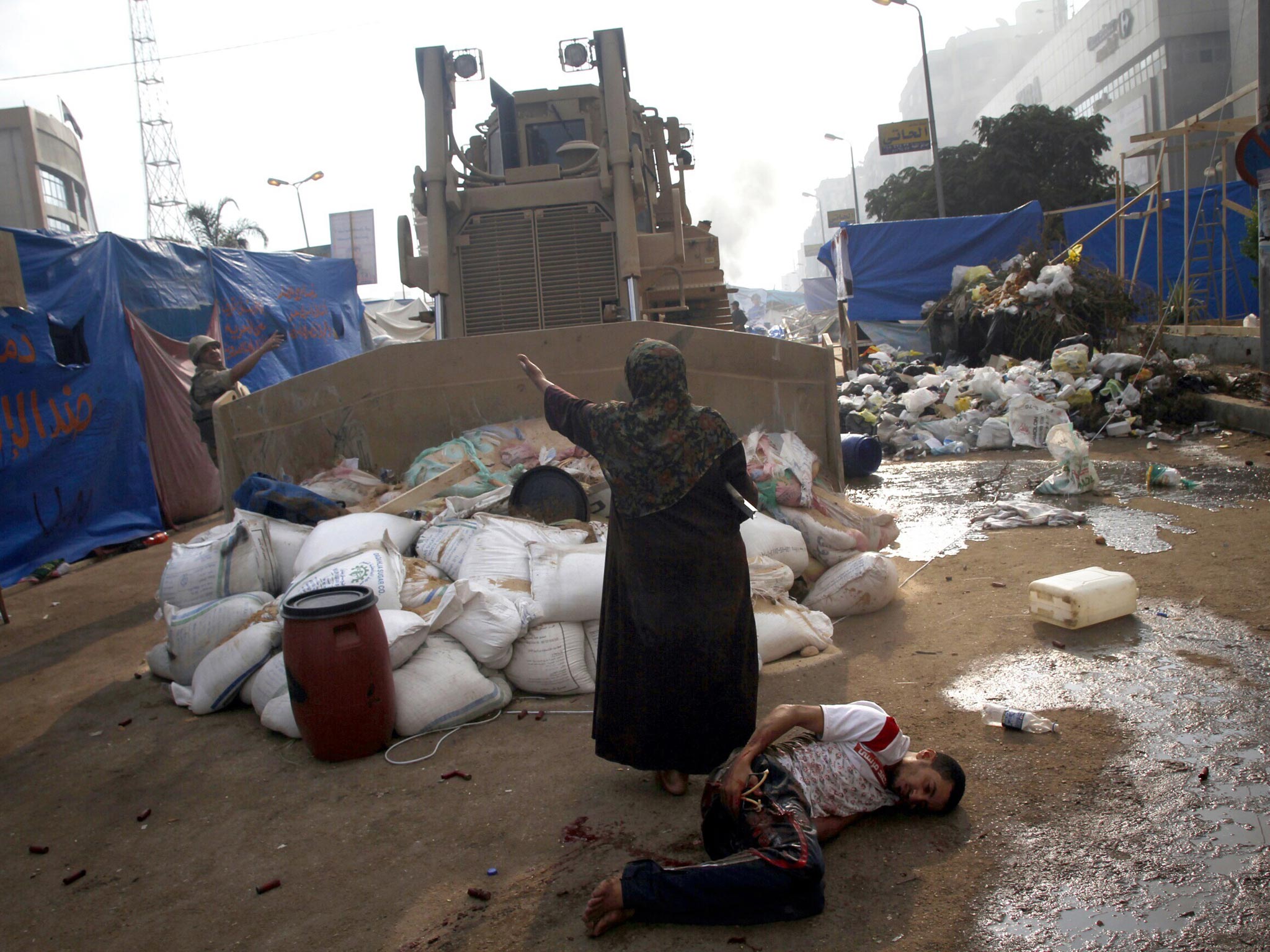 An Egyptian woman tries to stop a military bulldozer from hurting a wounded youth