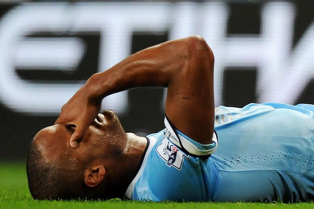 Vincent Kompany holds his head after picking up an injury after tackling Newcastle United's Sammy Ameobi 