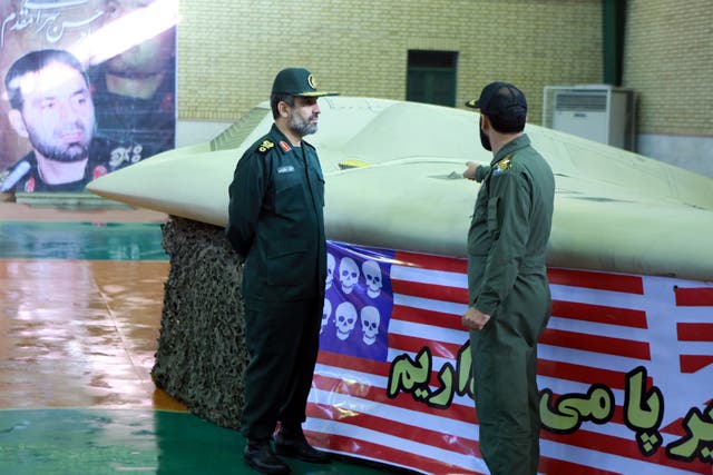 An undated picture received on December 8, 2011 shows a member of Iran's revolutionary guard (R) pointing at the U.S. RQ-170 unmanned spy plane as he speaks with Amirali Hajizadeh, a revolutionary guard commander, at an unknown location in Iran. The unman