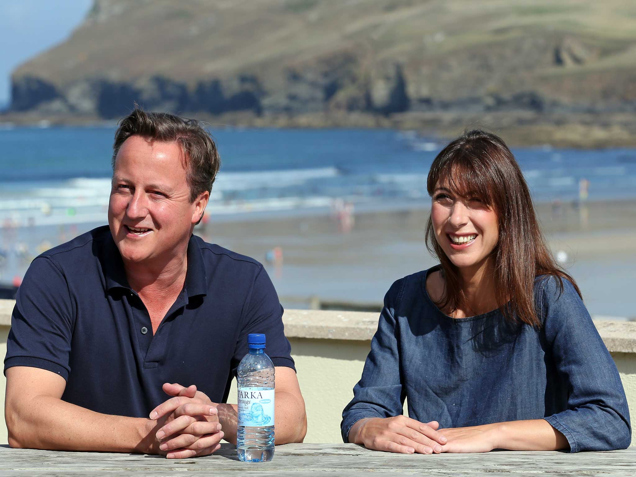 David Cameron and his wife Samantha sit on a bench outside a cafe overlooking the beach at Polzeath