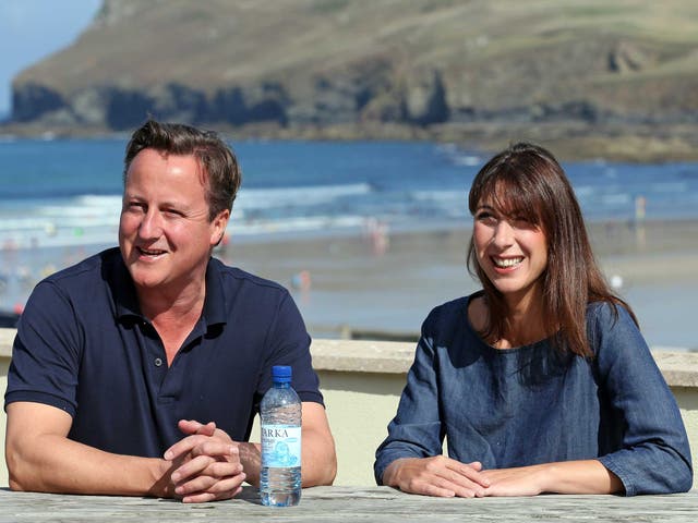 David Cameron and his wife Samantha sit on a bench outside a cafe overlooking the beach at Polzeath