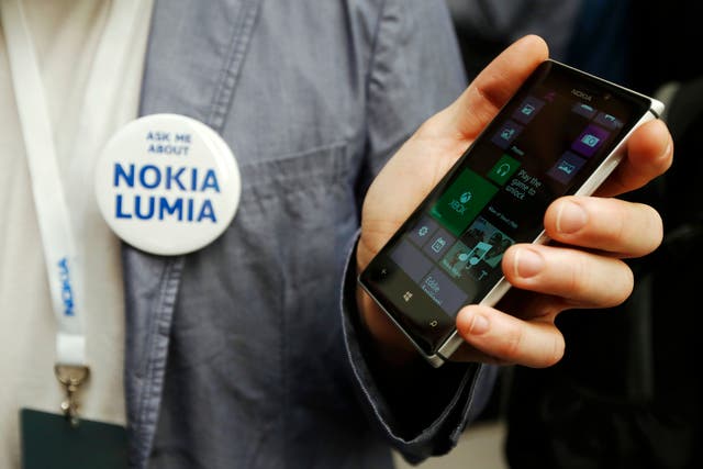 A worker poses with the new Nokia Lumia 925 at its launch in London May 14, 2013. Nokia unveiled a lighter, metal model in its Lumia smartphone range, as it tries to catch the eye of buyers to close the huge market lead of rivals Samsung and Apple Inc in 