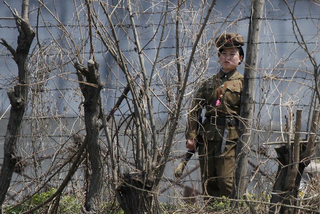 A North Korean prison policewoman stands guard behind fences at a jail on the banks of Yalu River