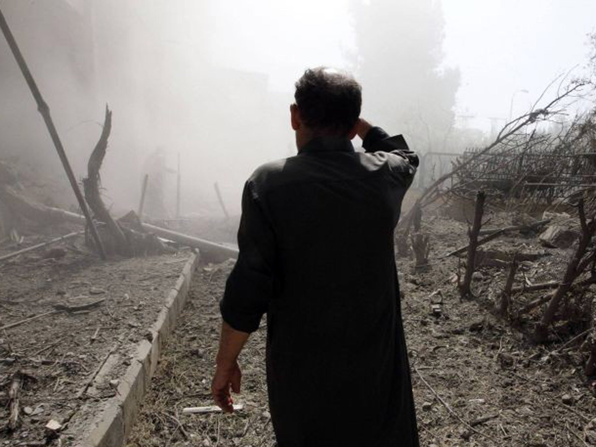 A man inspects a site hit by what activists said were missiles fired by Syrian Air Force fighter jets loyal to President Bashar al-Assad, in Raqqa province, eastern Syria on 21 August 2013