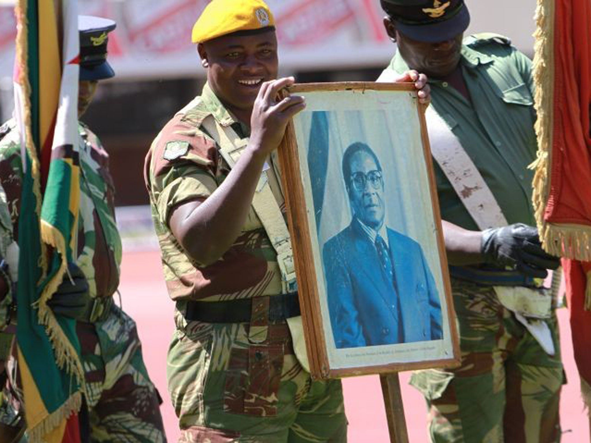 A soldiers holds a portrait of Zimbabwean President elect, Robert Mugabe during rehearsals for his inauguration in Harare, Wednesday, Aug. 21, 2013. Mugabe is expected to be inaugurated Thursday after Movement For Democratic Change (MDC) President Morgan Tsvangirai's case was dismissed by the Constitutional Court