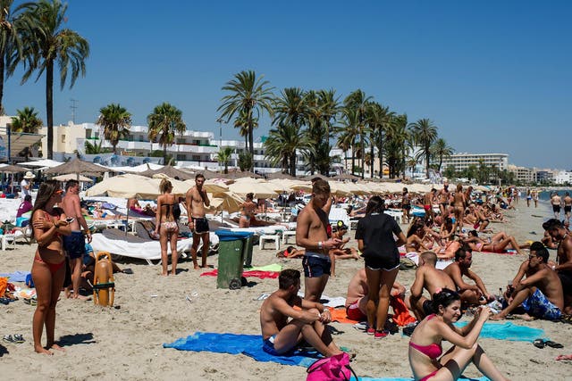 People sunbathe at Platja d'en Bossa beach in Ibiza, Spain