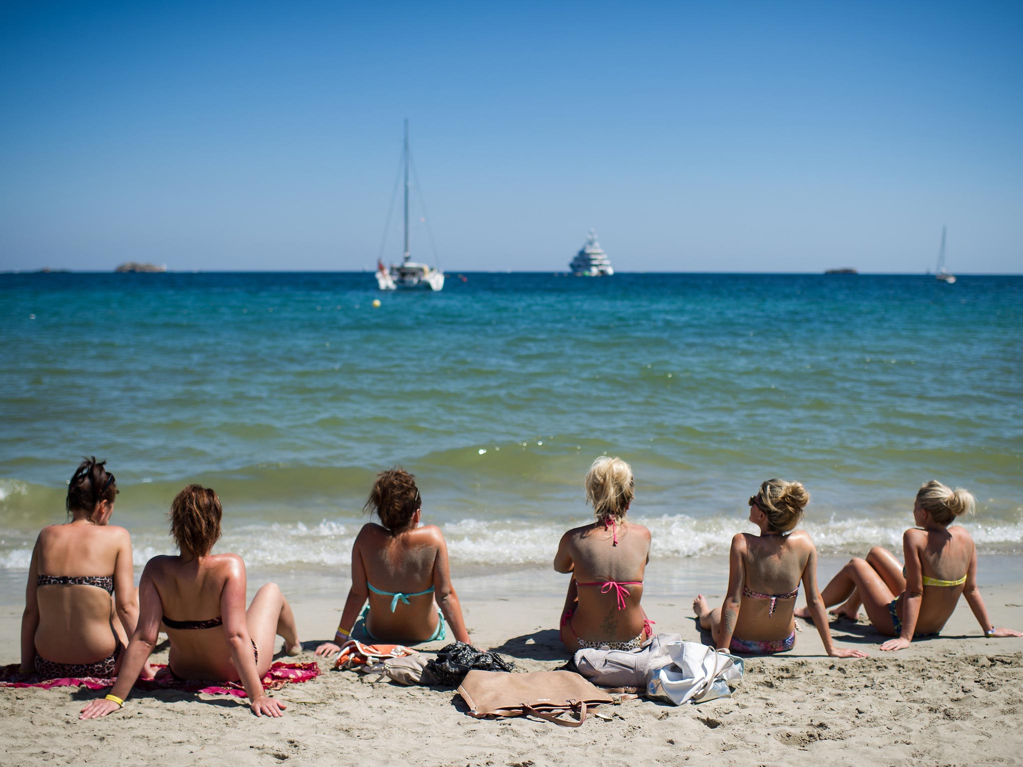 A group of tourists sunbathe at Platja d'en Bossa beach