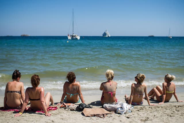 A group of tourists sunbathe at Platja d'en Bossa beach