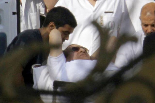 Egyptian medics escort Mubarak  into an ambulance after he was flown by a helicopter ambulance to the Maadi Military Hospital from Torah prison in Cairo