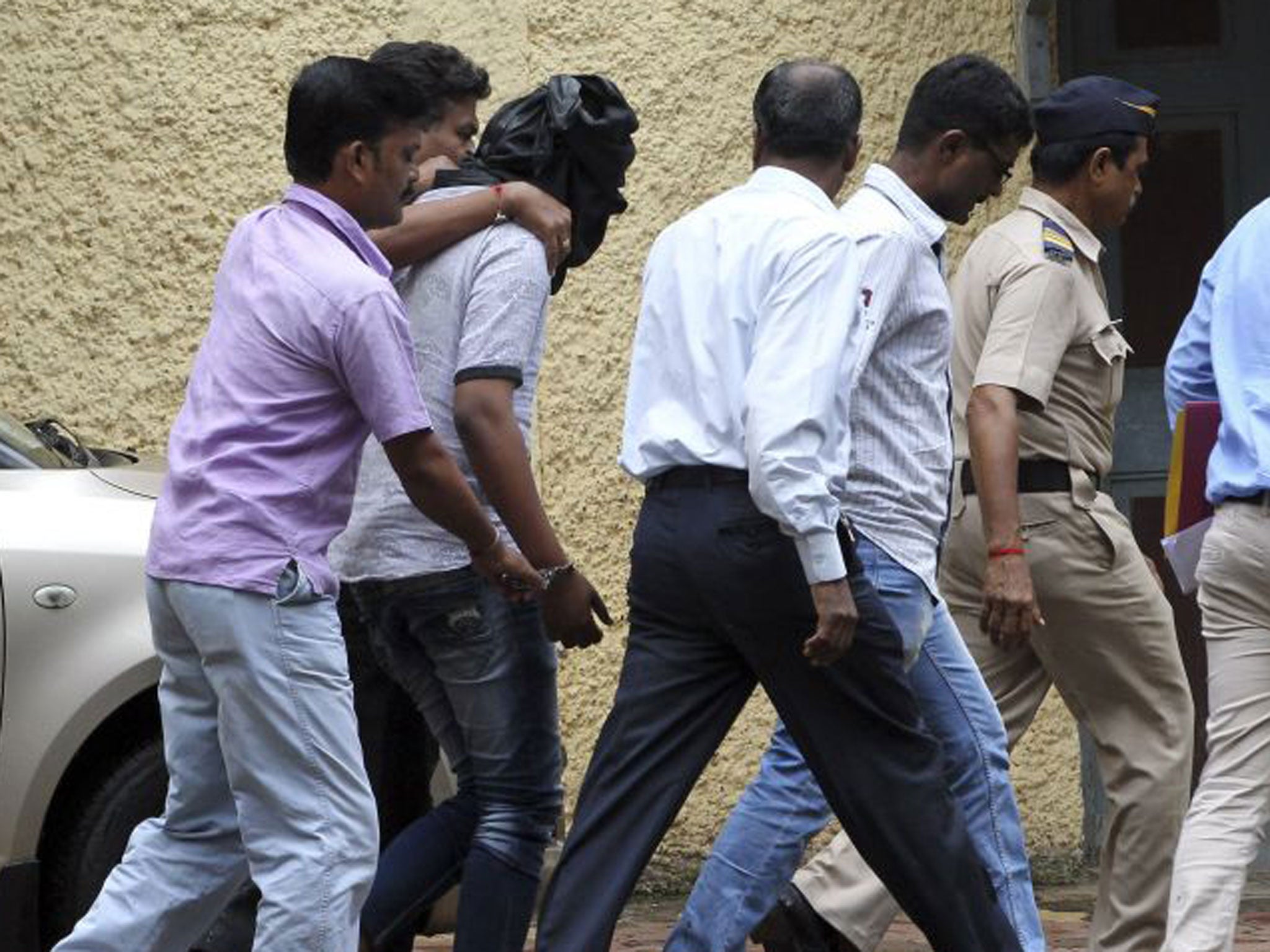 Police officials escort a man accused, head covered with black cloth, of the gang rape of a young photojournalist in Mumbai