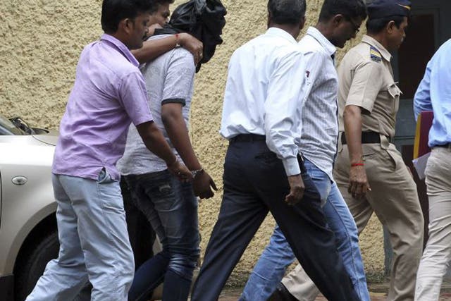 Police officials escort an accused, head covered with black cloth, in the gang rape of a young photojournalist in Mumbai