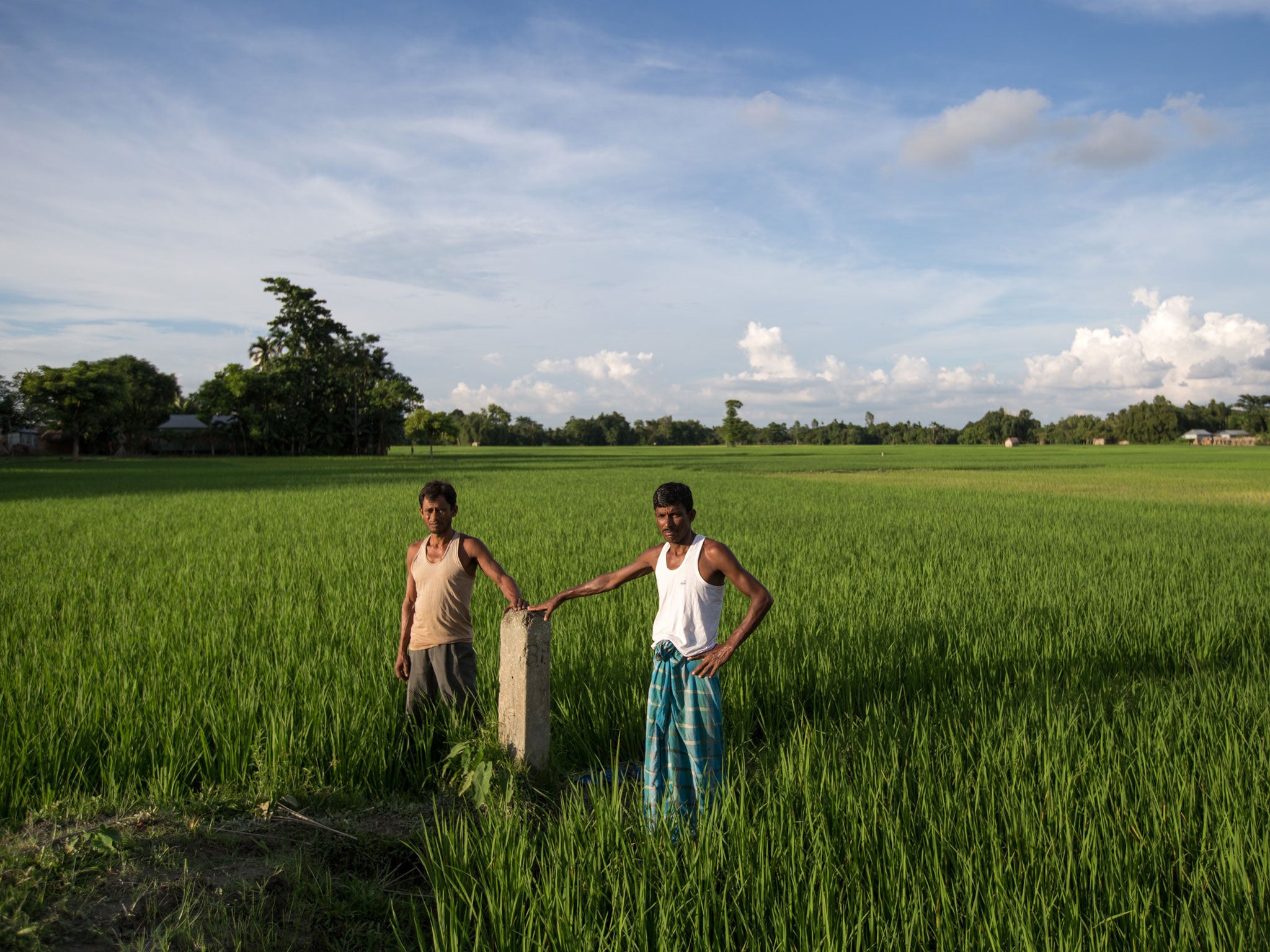 Villagers stand at a marker post at Masaldanga – an Indian enclave surrounded by Bangladeshi territory Graham Crouch)