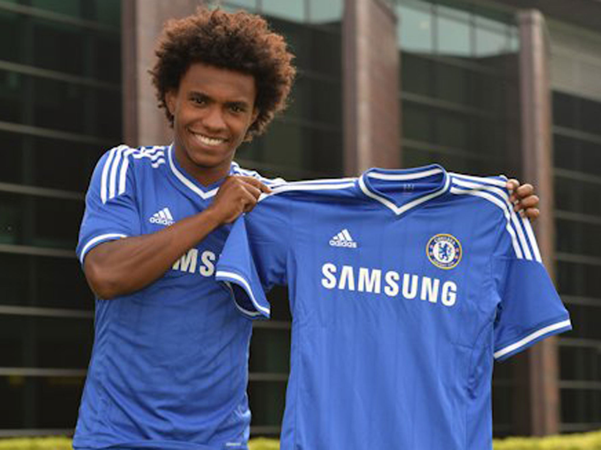 Willian holds the Chelsea shirt after completing his £32m move