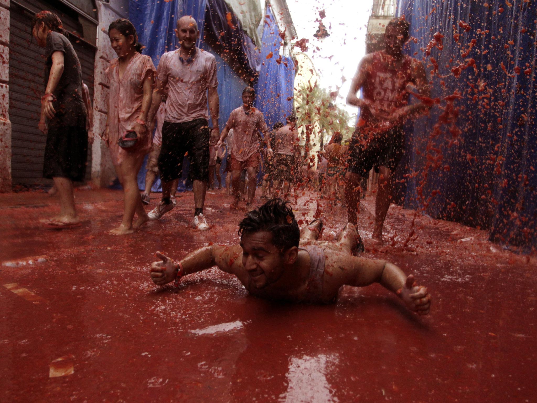 A reveller plays in tomato pulp after the annual "Tomatina" (tomato fight) in the Mediterranean village of Bunol, near Valencia