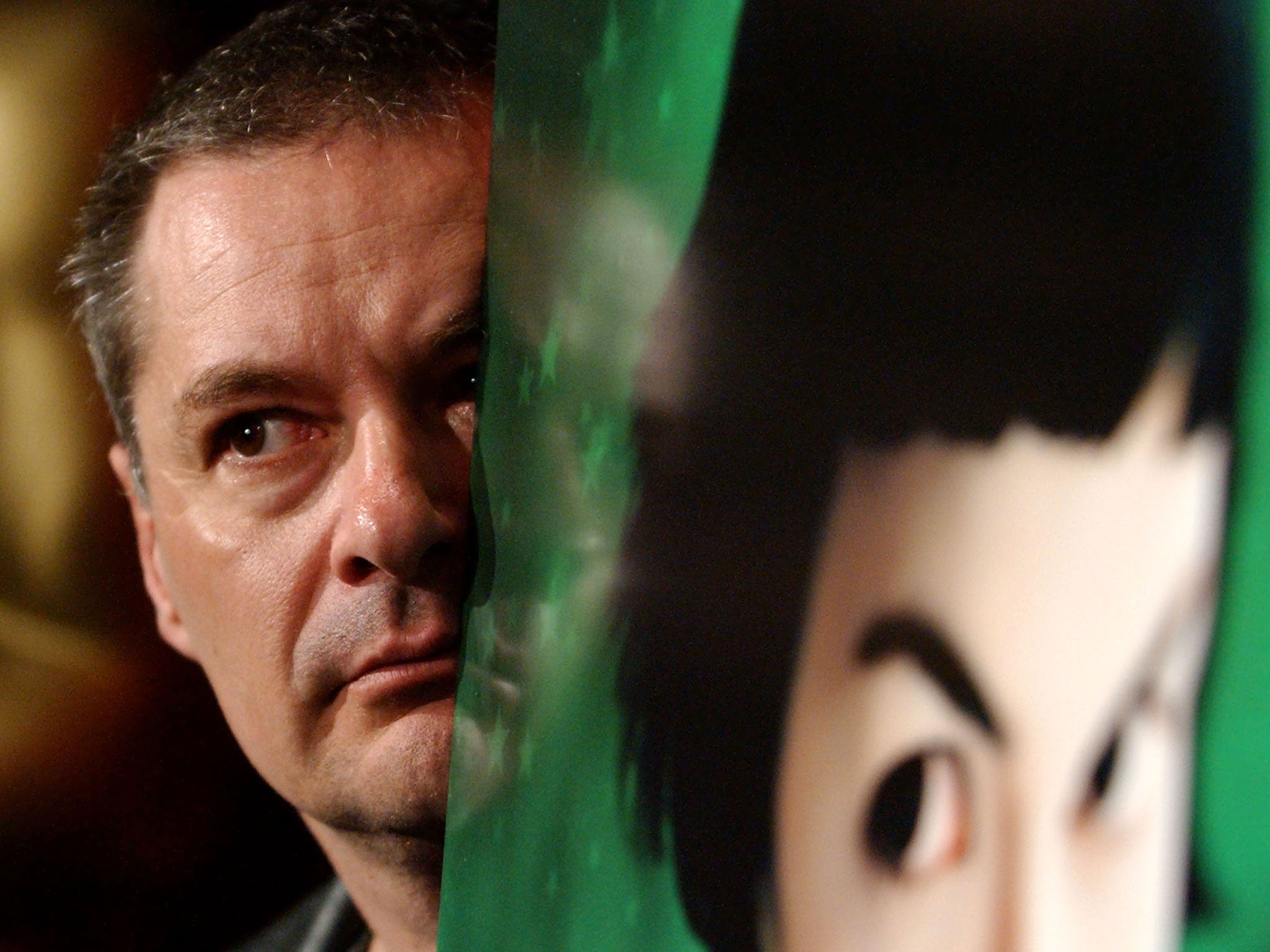 French Director Jean-Pierre Jeunet peers at the media from behind a poster of his film 'Amelie', 2002