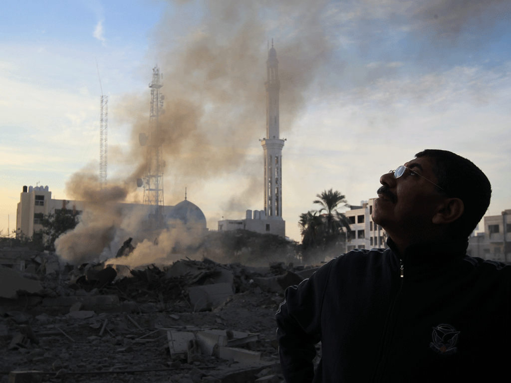 A Palestinian man looks to the sky amidst debris caused by the air strike in November of last year